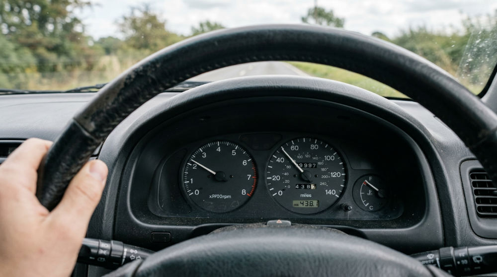 A vehicle dashboard showing the 100,000 mile mark, representing the mileage milestone where maintenance costs spike for many vehicles.